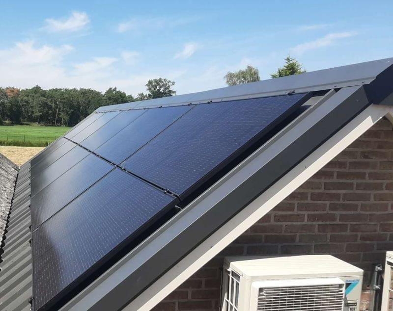 Nahaufnahme montierter Full-Black-Module, darunter die Außeneinheit einer Wärmepumpe